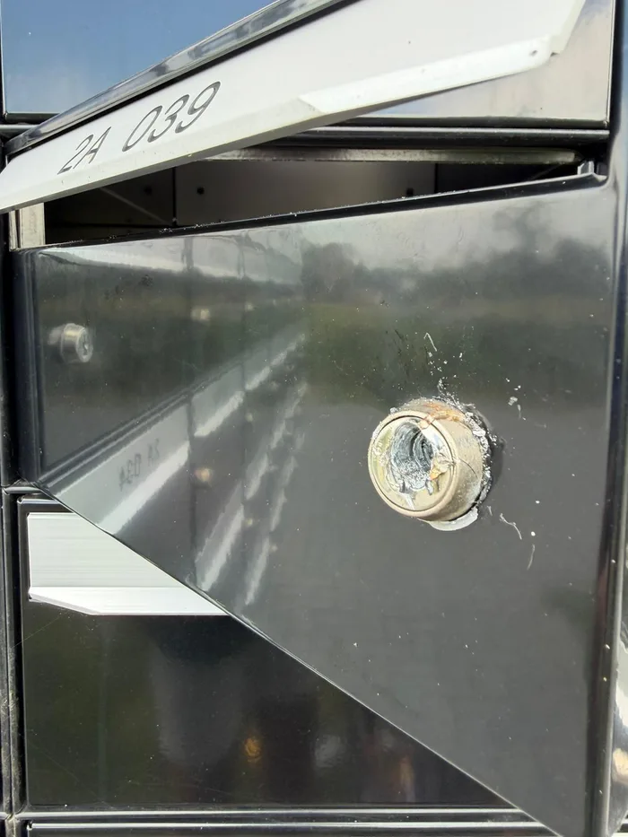 Detail van een beschadigd slot in een geopende brievenbus